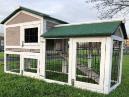 grey and white rabbit hutch with green roof and rabbit run